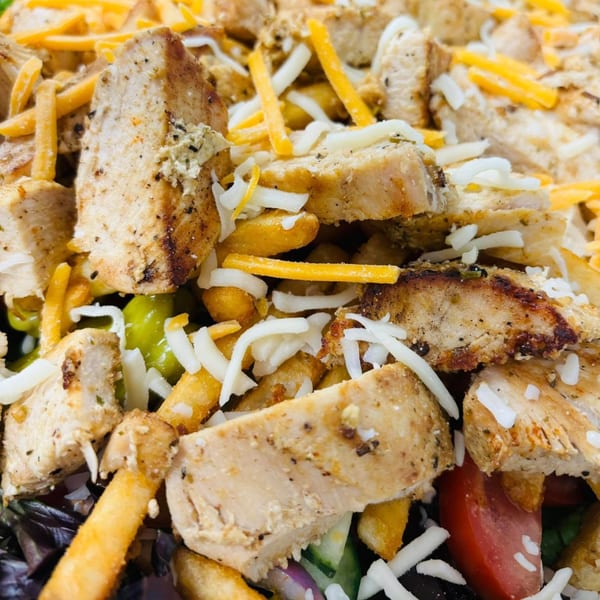 Close-up of Sims Cafe's chicken salad with fries, cheese, and vegetables.