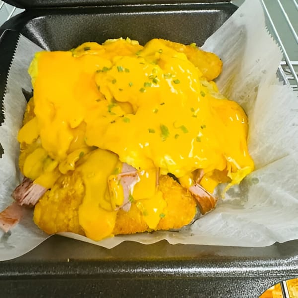 Sims Cafe's breakfast croissant with ham, eggs, and melted cheese, topped with chives.